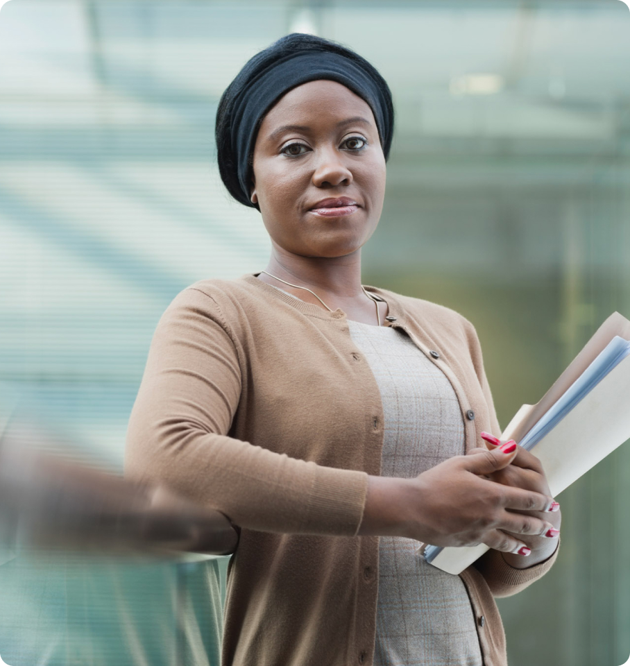 Image of a female healthcare professional, leaning against a railing and smiling at the camera.