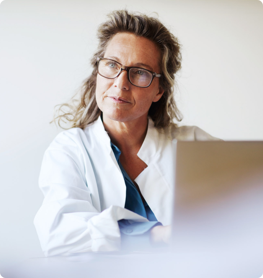 Image of a female dental professional taking notes on a computer while listening to a patient.