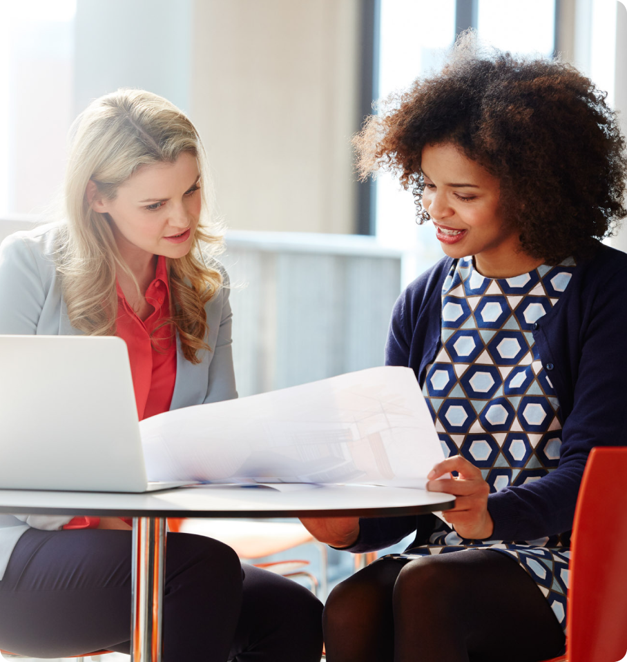 Image of two female healthcare professionals sitting at a desk collaborating on an assignment.